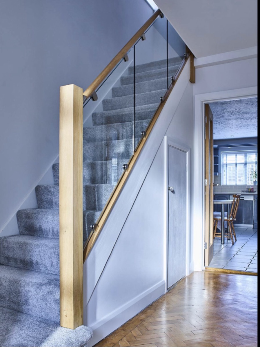 Oak and glass balustrade above a herringbone parquet hallway with understair joinery